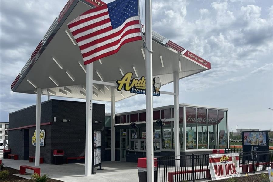 exterior of a building with a tall awning and a sign that says andys frozen custard and an american flag